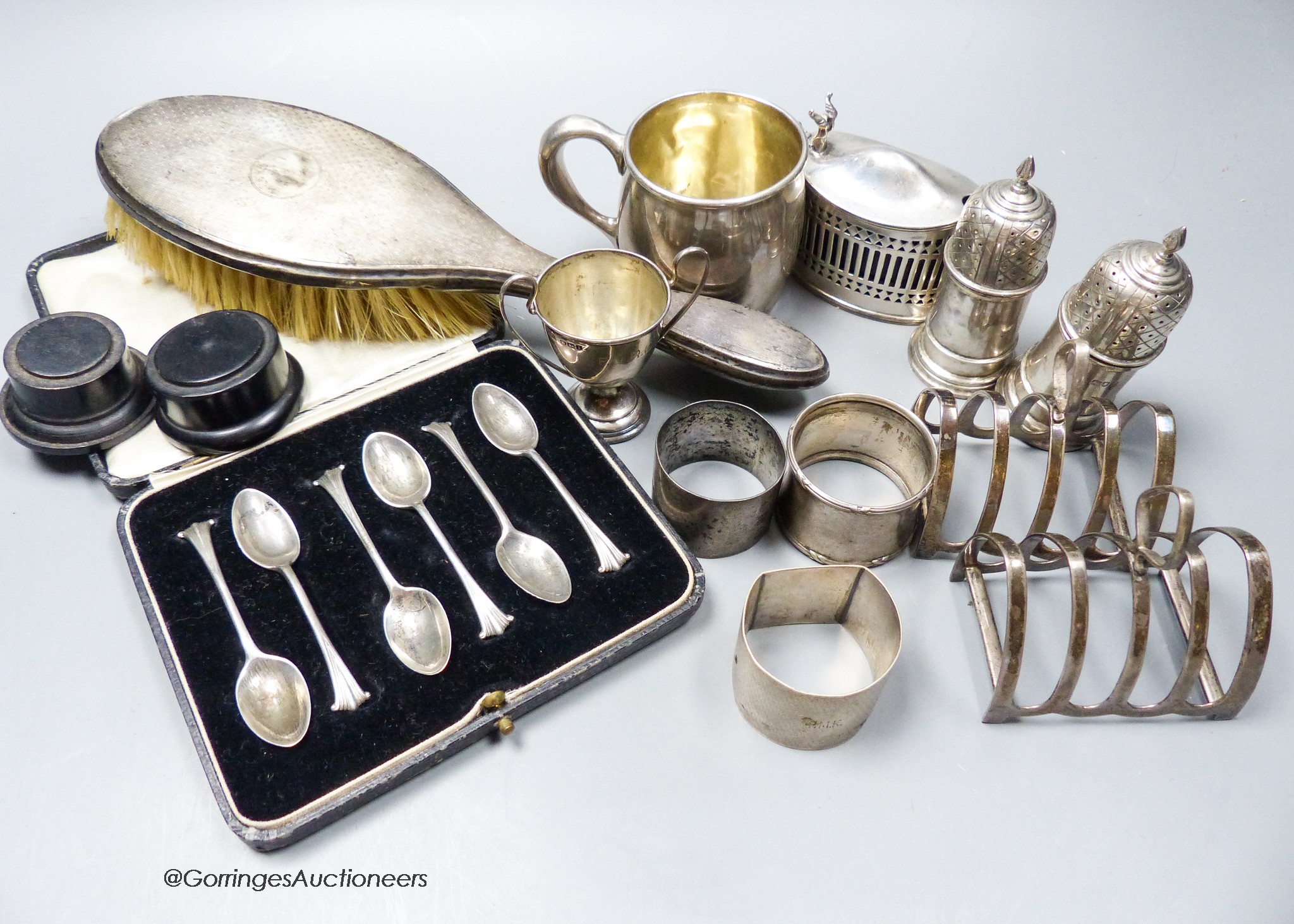 Small silver including a pair of silver toastracks, silver mug, pair of peppers, trophy cup, mustard pot, three napkin rings, set of six coffee spoons and a mounted brush